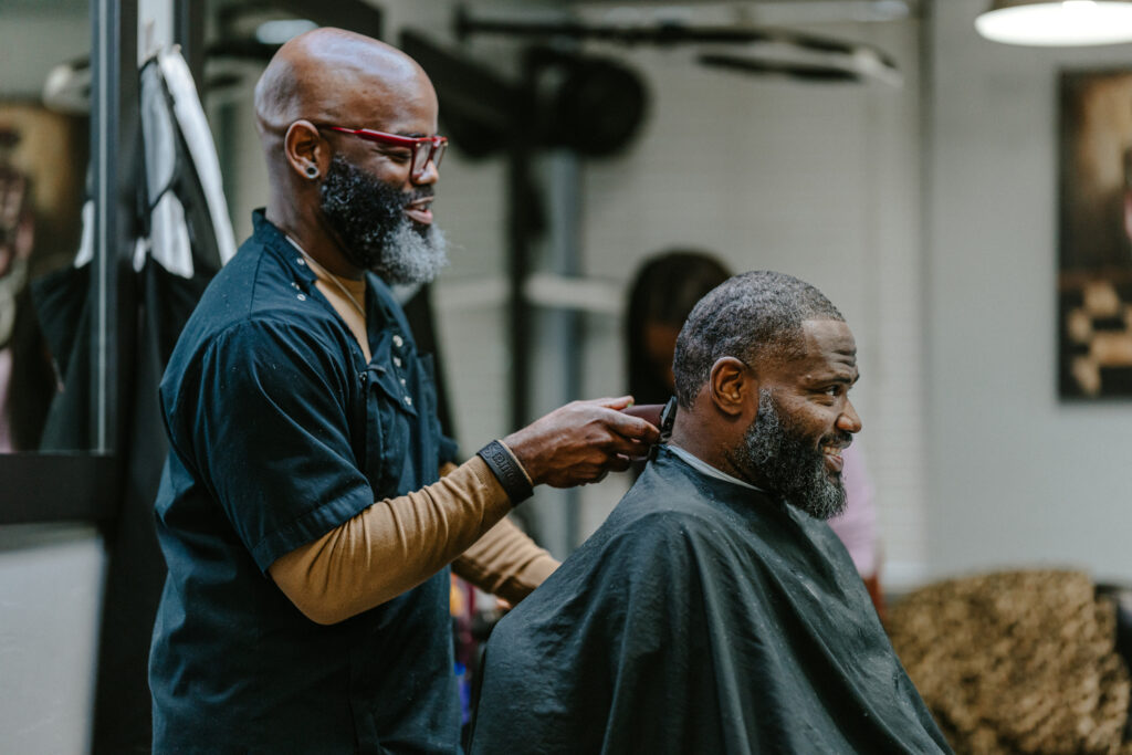 A barber is cutting hair for a client in a cozy barbershop setting.
