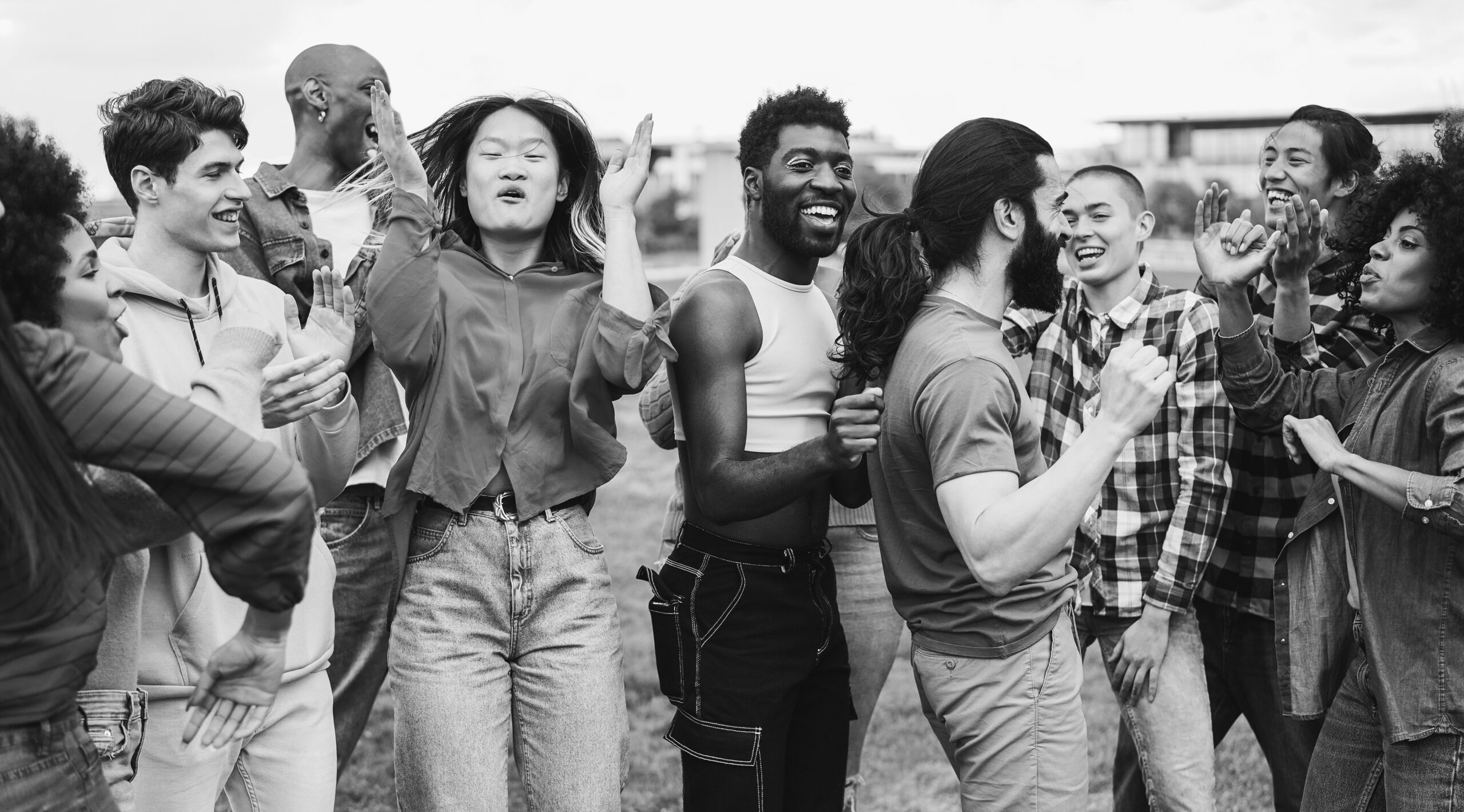 A joyful group of diverse people dancing and celebrating together outdoors.